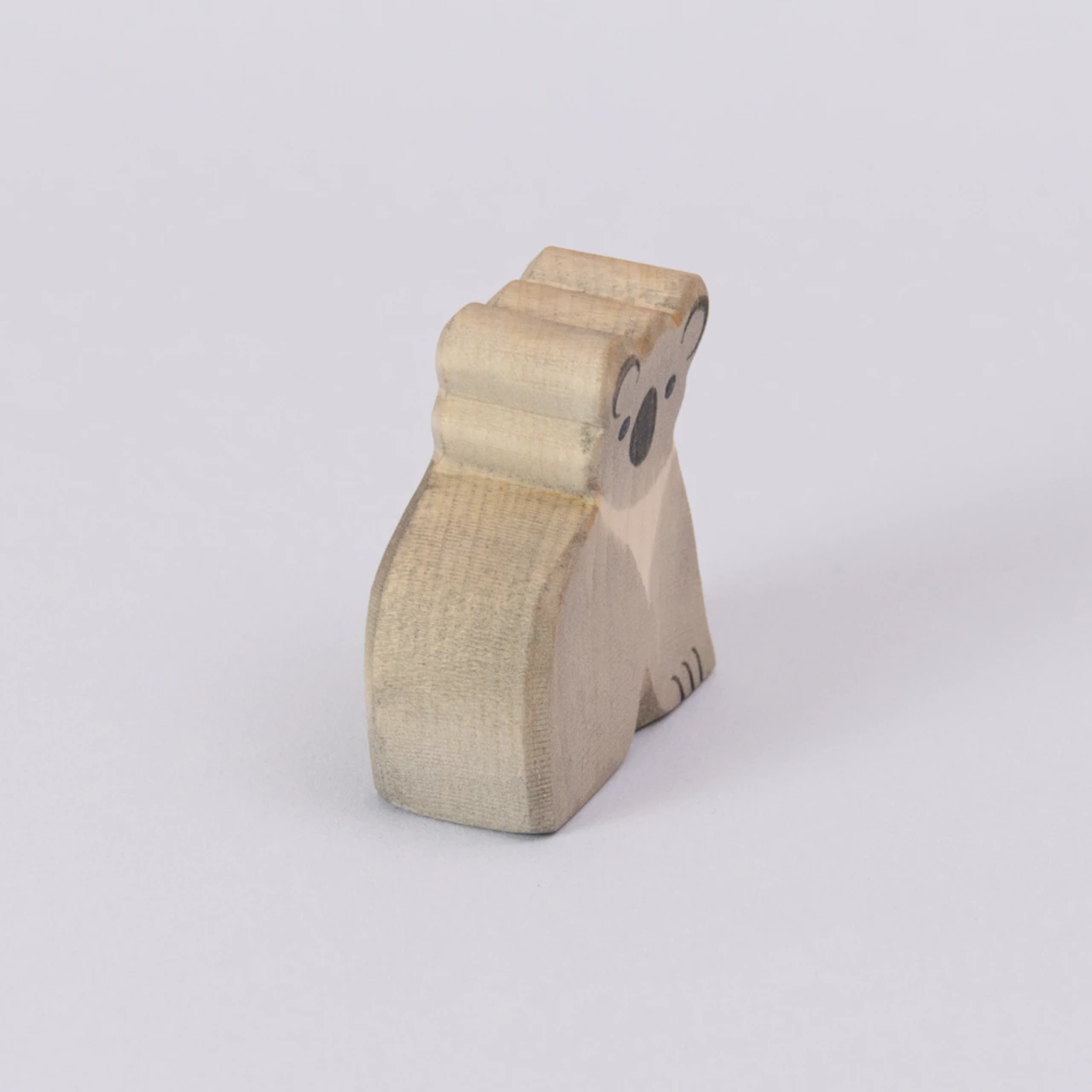 Ein Koala von Ostheimer, aus Holz zum Spielen, in den Farben grau und schwarz für das Gesicht. Der Koala wird schräg von der Seite gezeigt.